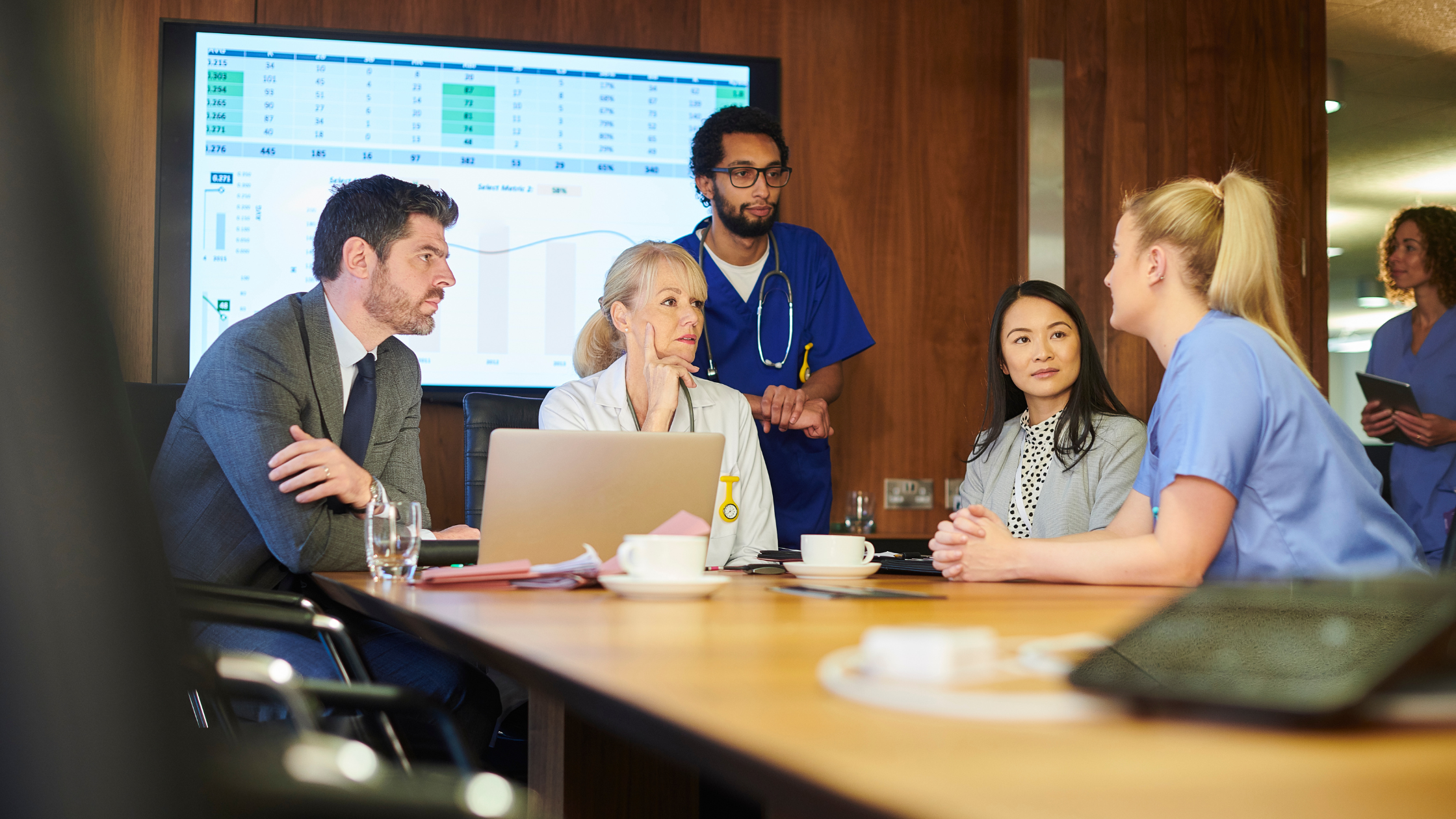 Hospital team of 5 people gathered around a table discussing medication management and operational improvements.