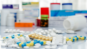 Medication at a Central Distribution Center (CDC) for hospital pharmacy inventory management. Including pill packs, bottles of pills, prescriptions, and more all laying on a counter.